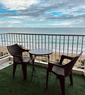 A balcony with two wicker chairs and a small round table, overlooking a beach and the ocean. - Blueberry Miracle Balcony Oceanfront beach view (Carolina City)
