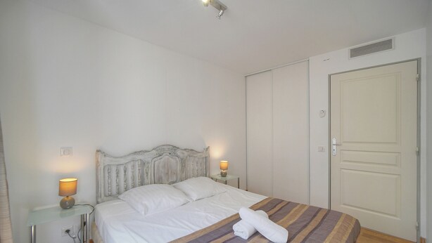 Uma cama bem arrumada com um cobertor listrado, um abajur e uma toalha dobrada sobre a cama.