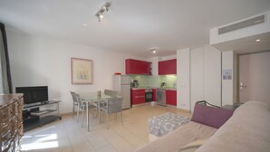 Um espaço compacto com cozinha compacta, área de jantar, sofá e televisão.