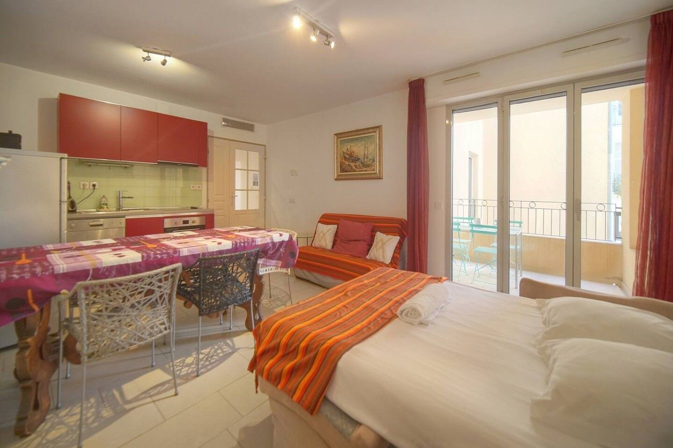 Habitación de hotel con cama, una mesa de comedor con sillas, zona de cocina y balcón con vistas.