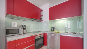 Una cocina moderna con armarios rojos, electrodomésticos de acero inoxidable y lavavajillas.
