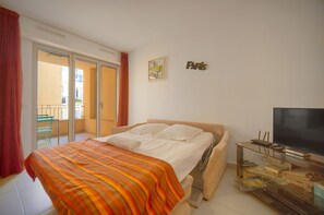 Ein Schlafzimmer mit einem Bett, einem Fernseher, einer Glasschrank und einer Schiebetür zum Balkon.