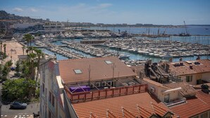 A marina with numerous boats docked, a building with a red-tiled roof, and a clear blue sky. - FRGK - SUQUET DUPLEX WITH VIEWS OF THE HARBOR AND THE PALACE - 2BR (Cannes)