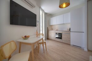 Eine moderne Küche mit weißen Schränken, einem eingebauten Backofen und einem Essbereich mit Tisch und Stühlen.
