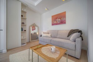 Ein modernes Wohnzimmer mit einer Couch, einem Couchtisch, einem Bücherregal und einem Spiegel.