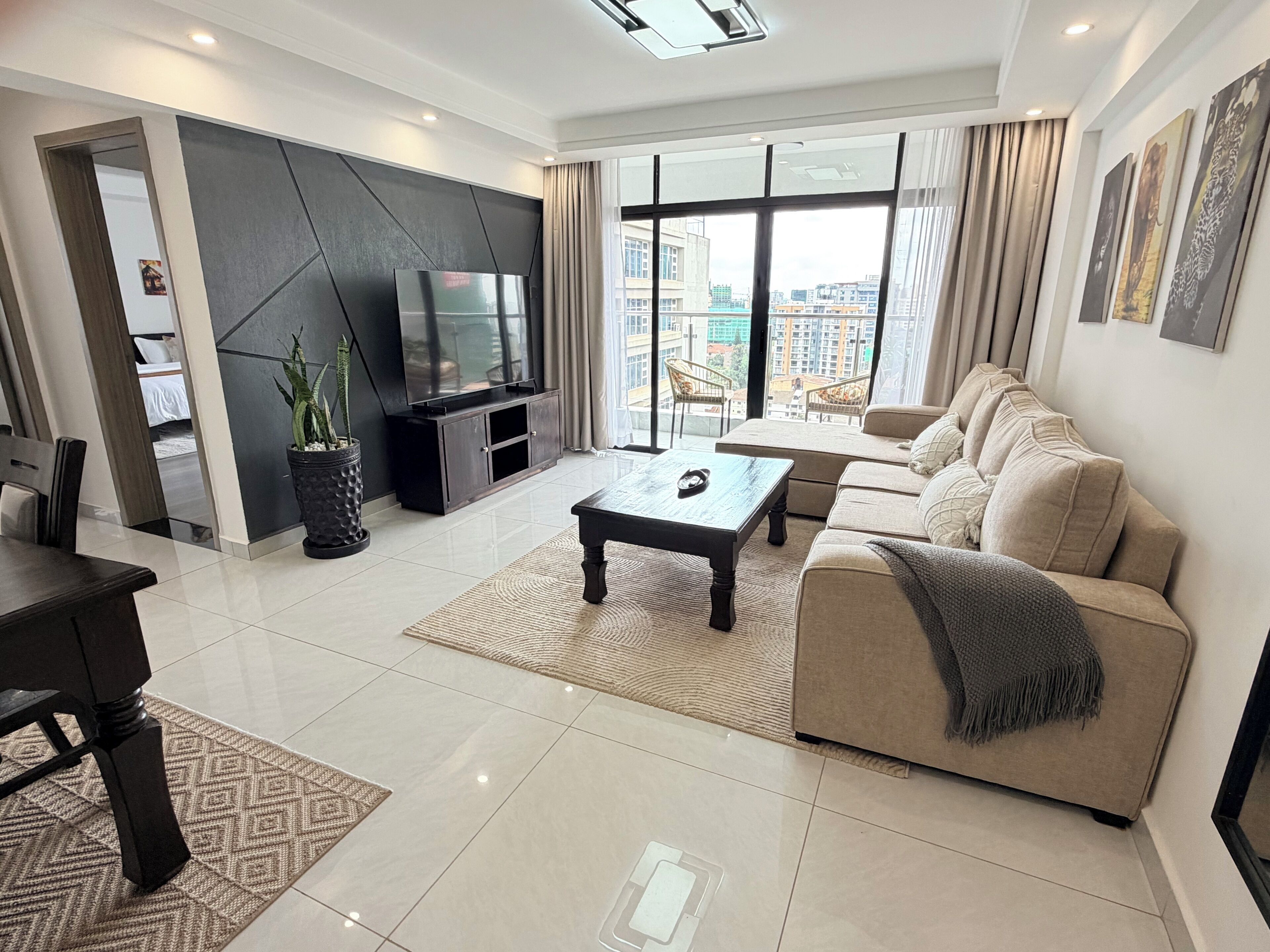 A modern living room with a sofa, coffee table, TV, and large windows.