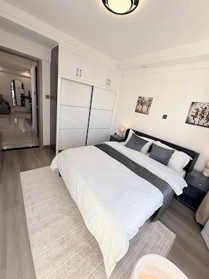 A bedroom with a bed, nightstands, a wardrobe, and artwork on the wall. - Spacious 2BR Westlands (Nairobi)
