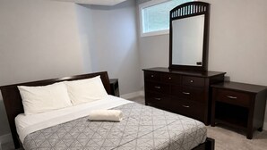 Une chambre à coucher avec un lit, une commode, un miroir et une fenêtre.