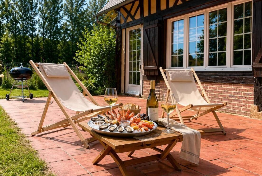 Een terras met twee comfortabele stoelen, een tafel met zeevruchten, wijnglazen en een barbecue.