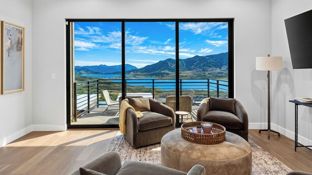 Ein modernes Wohnzimmer mit einer großen Schiebeglaswand, die auf einen Balkon mit herrlichem Bergblick führt.
