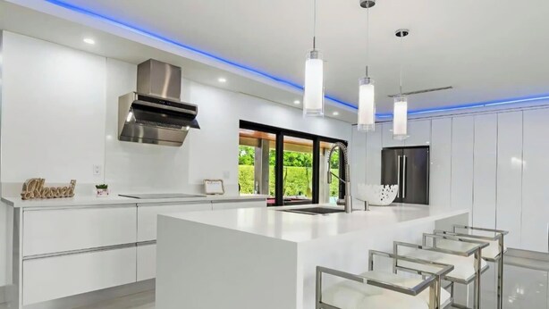 Una cocina moderna con una isla central, iluminación colgante y vistas al exterior.