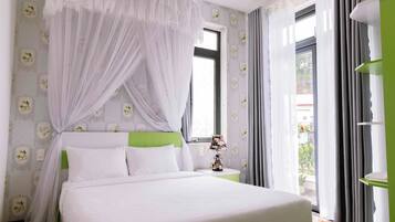 A bedroom with a bed, a nightstand, a lamp, a window with curtains, and a green accent wall.