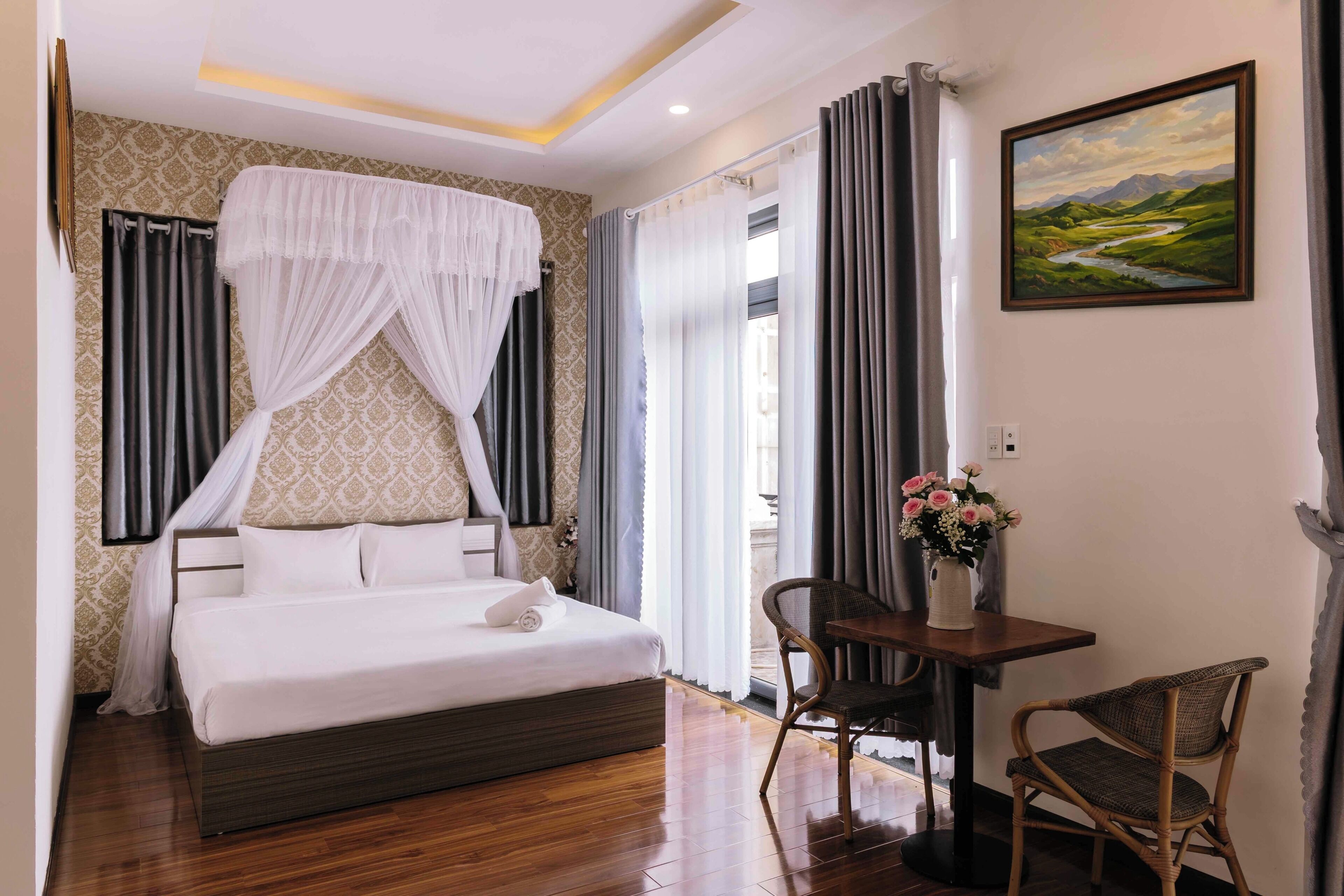 A bedroom with a bed, a chair, a table, and a painting on the wall.