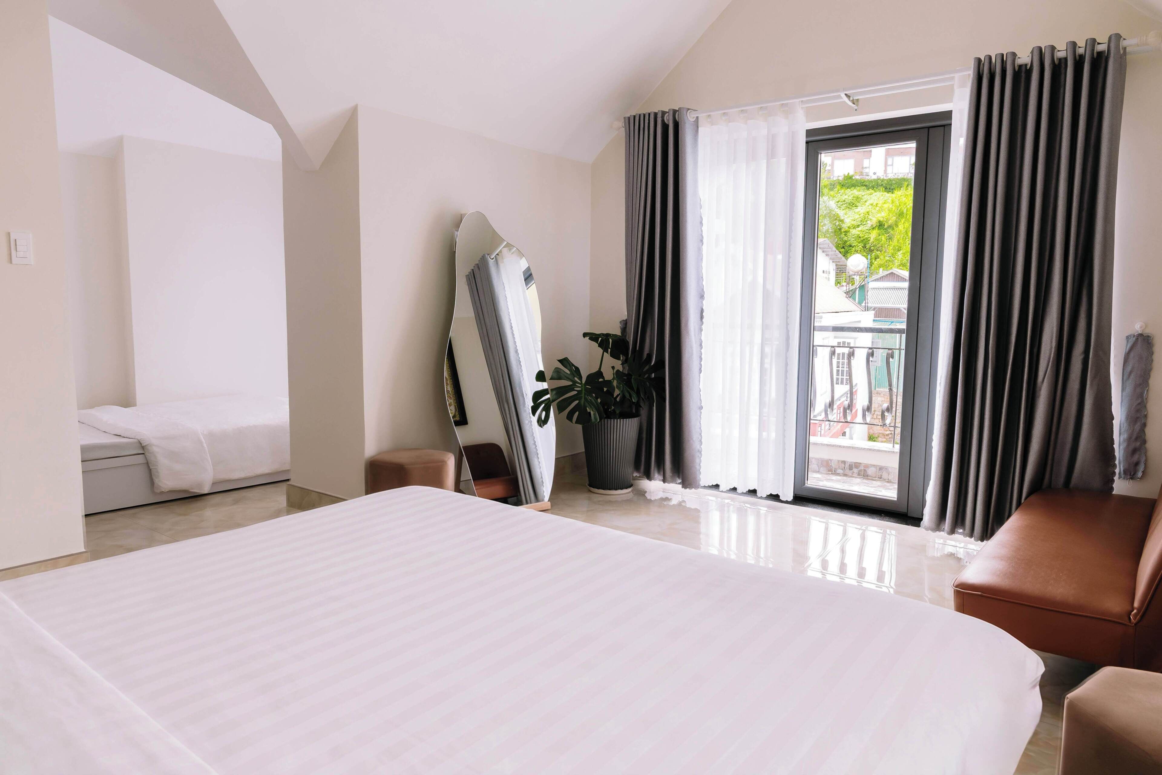 Een hotelkamer met een groot bed, een bank, een potplant en uitzicht op een balkon.