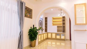 A hotel lobby with a reception desk, a large potted plant, and a decorative ceiling. - Hoanglee Villa (Mang Yang)