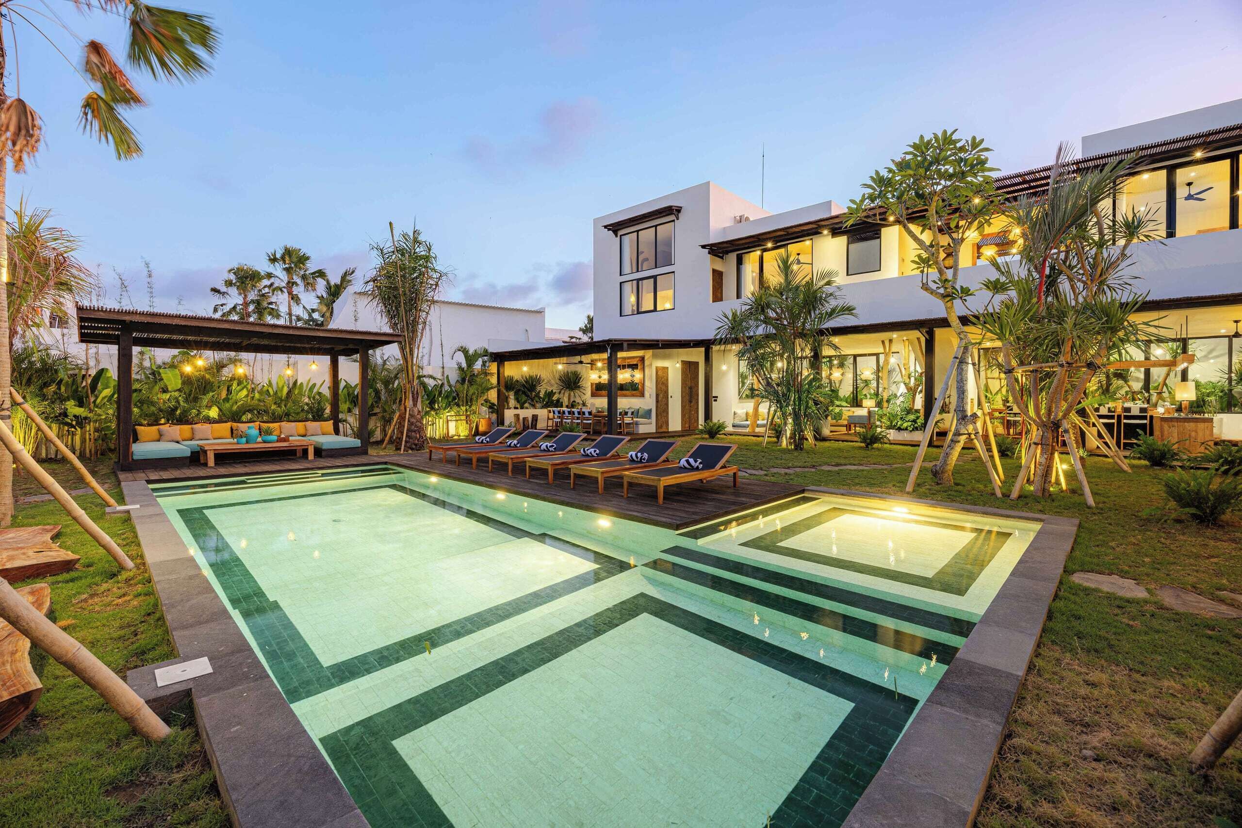 A modern hotel with a swimming pool, lounge area, and outdoor seating.