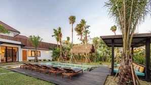 A modern house with a swimming pool, lounge chairs, and palm trees. - Brand-New LUX 5BR Villa with Grand Pool & Garden (Kerobokan)