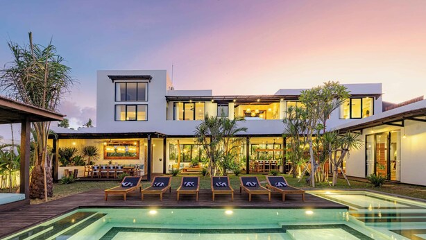 A modern house with a swimming pool, lounge chairs, and a patio area. - Brand-New LUX 5BR Villa with Grand Pool & Garden (Kerobokan)