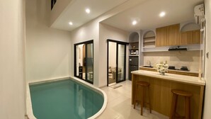 Cocina moderna con isla integrada, piscina y puerta corrediza de vidrio que da a un balcón.