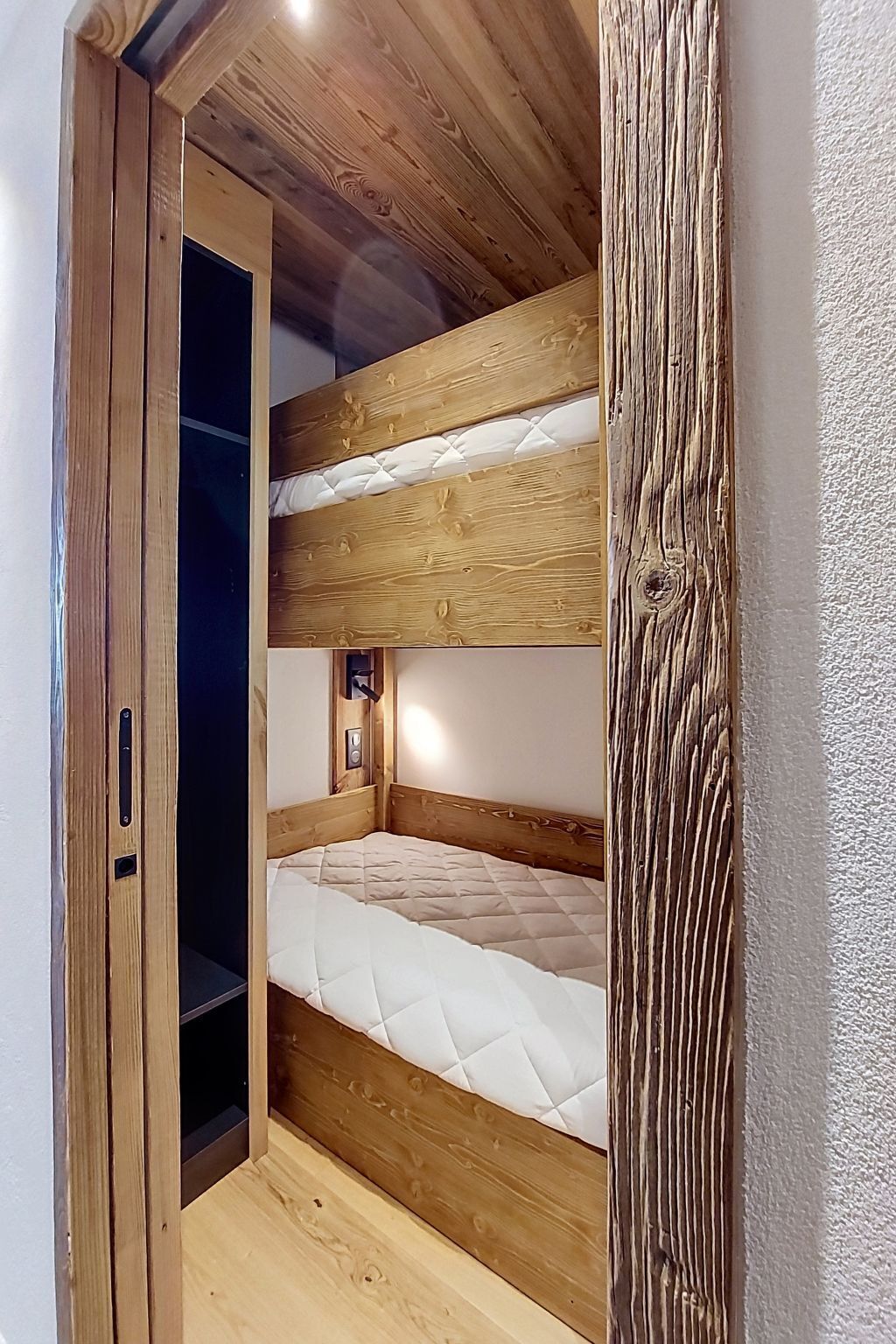 A bunk bed room with wooden walls and a door.
