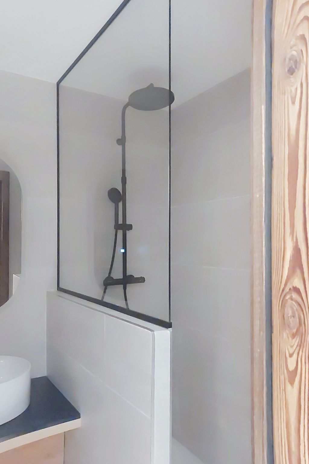Un baño con ducha, lavamanos y espejo.