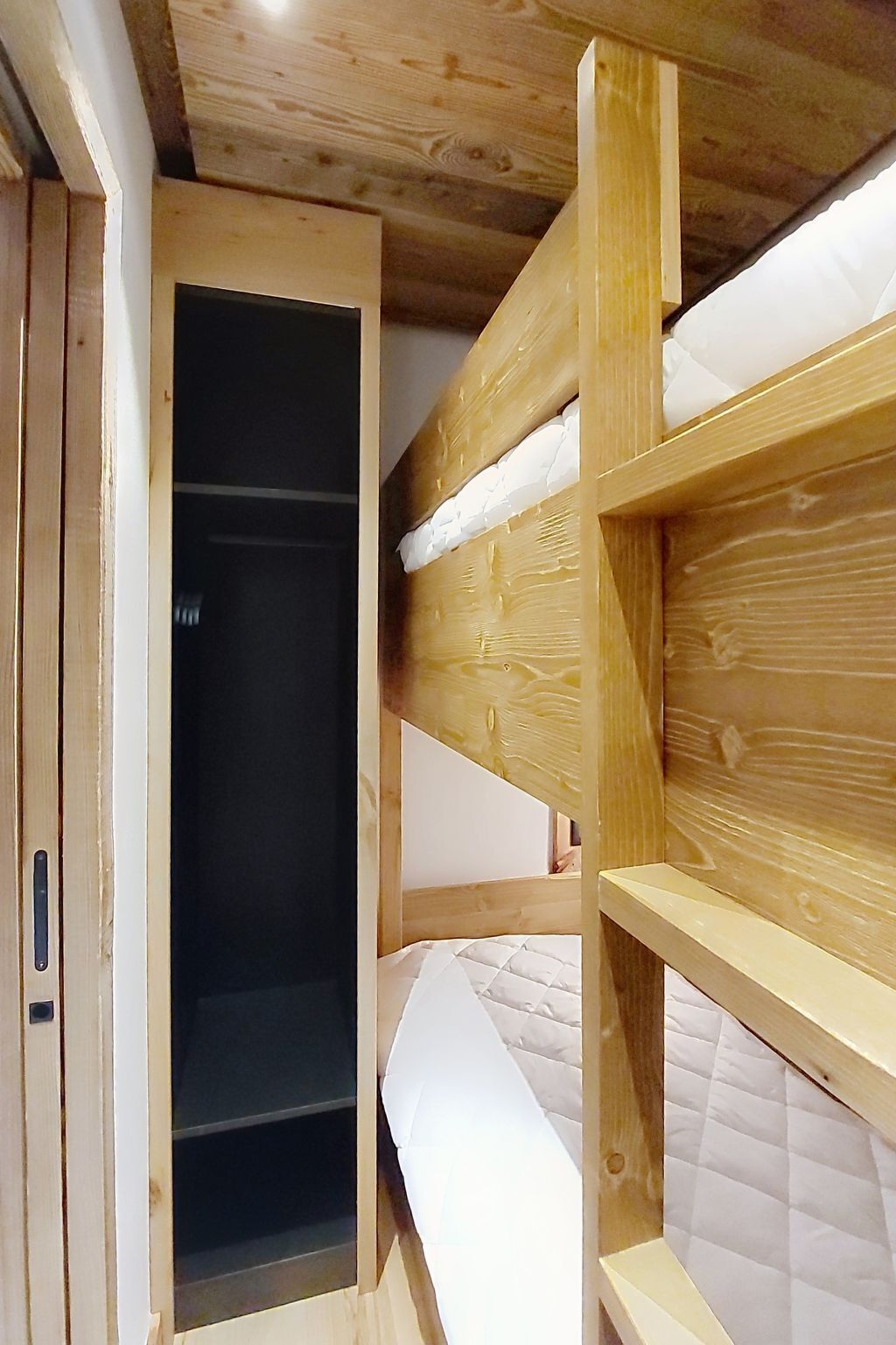 A bunk bed with a wooden frame and a mattress.