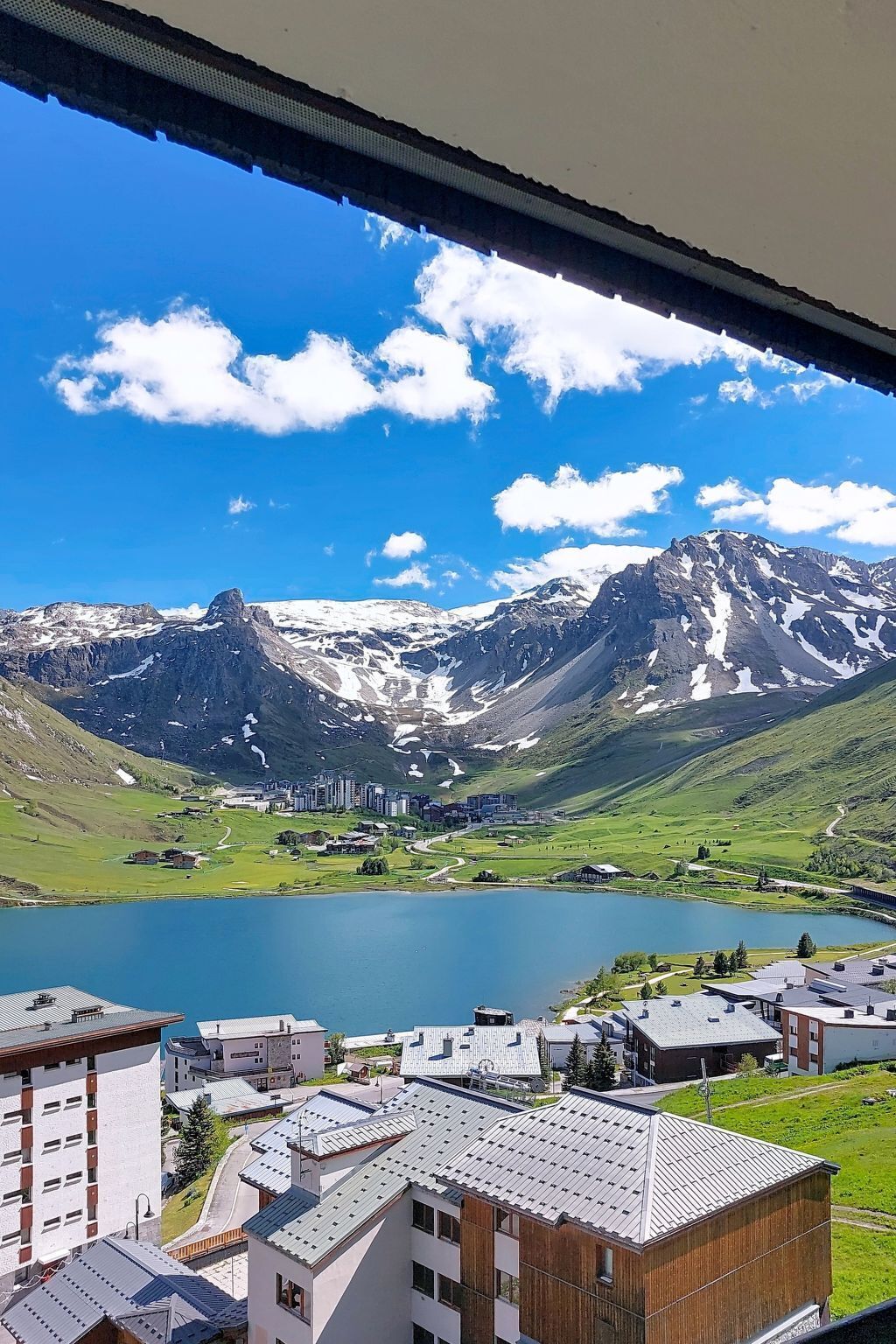 A view of a mountainous landscape with a lake, buildings, and a clear sky.
