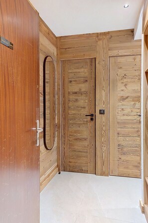 Ein Zimmer mit Holztür, Spiegel und Fliesenboden.