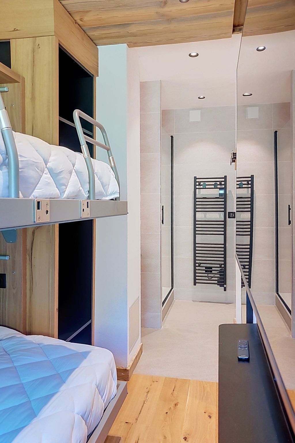 A modern bedroom with bunk beds, a wooden ceiling, and a walk-in closet.