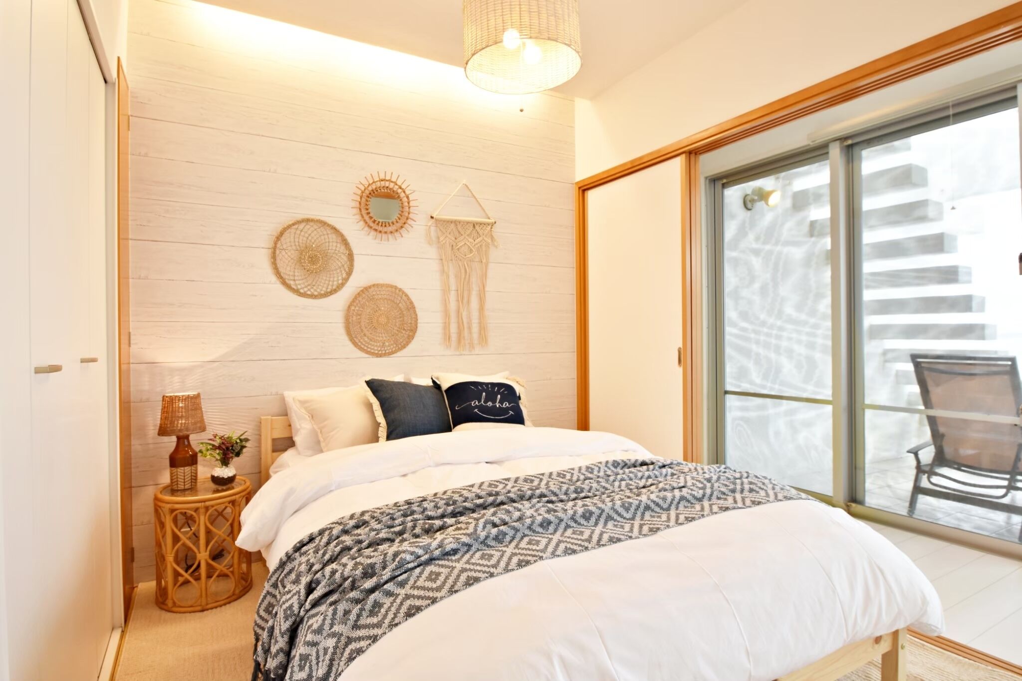 A bedroom with a bed, bedside table, wall decor, and a view through a sliding glass door.
