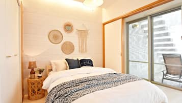 A bedroom with a bed, bedside table, wall decor, and a view through a sliding glass door.