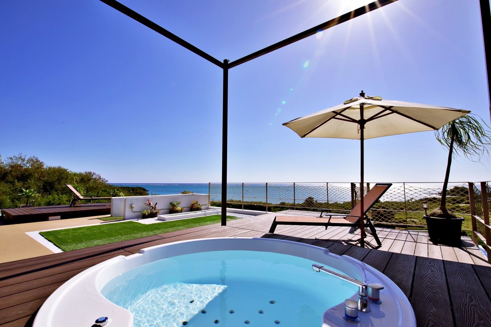 Een hottub op een houten terras met uitzicht op de oceaan.