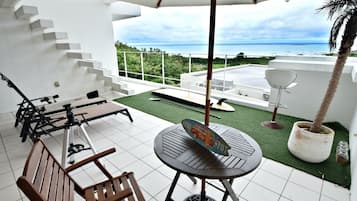A terrace with a table and chairs, a telescope, and a view of the ocean.