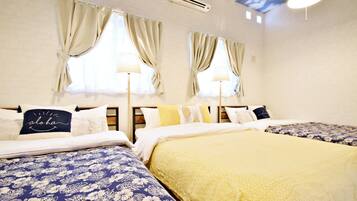 A hotel room with two beds, each with a different patterned bedspread, a ceiling with a cloud design, and a wall-mounted air conditioner.