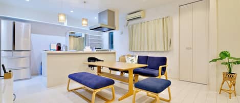 A modern kitchen with a dining area, featuring a wooden table and blue upholstered chairs.