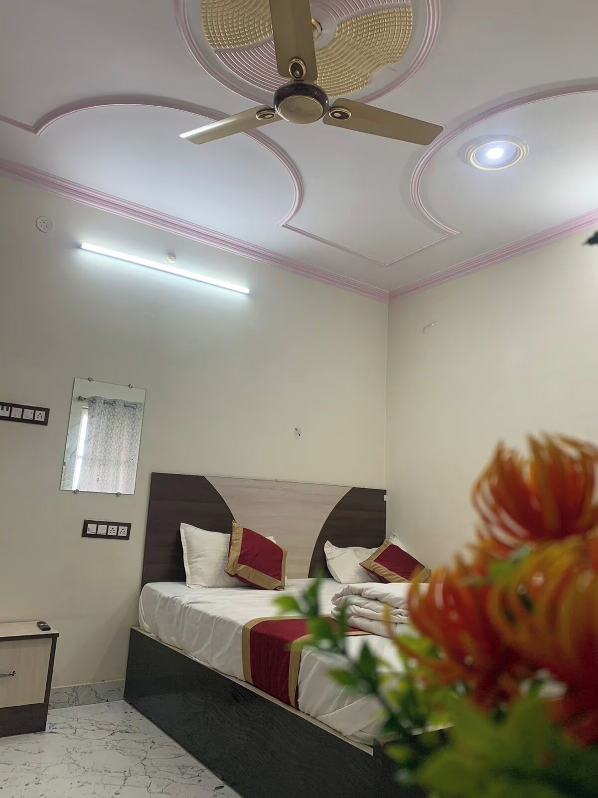 Ein Hotelzimmer mit Bett, Deckenventilator, Einbaustrahlern und einem Spiegel.