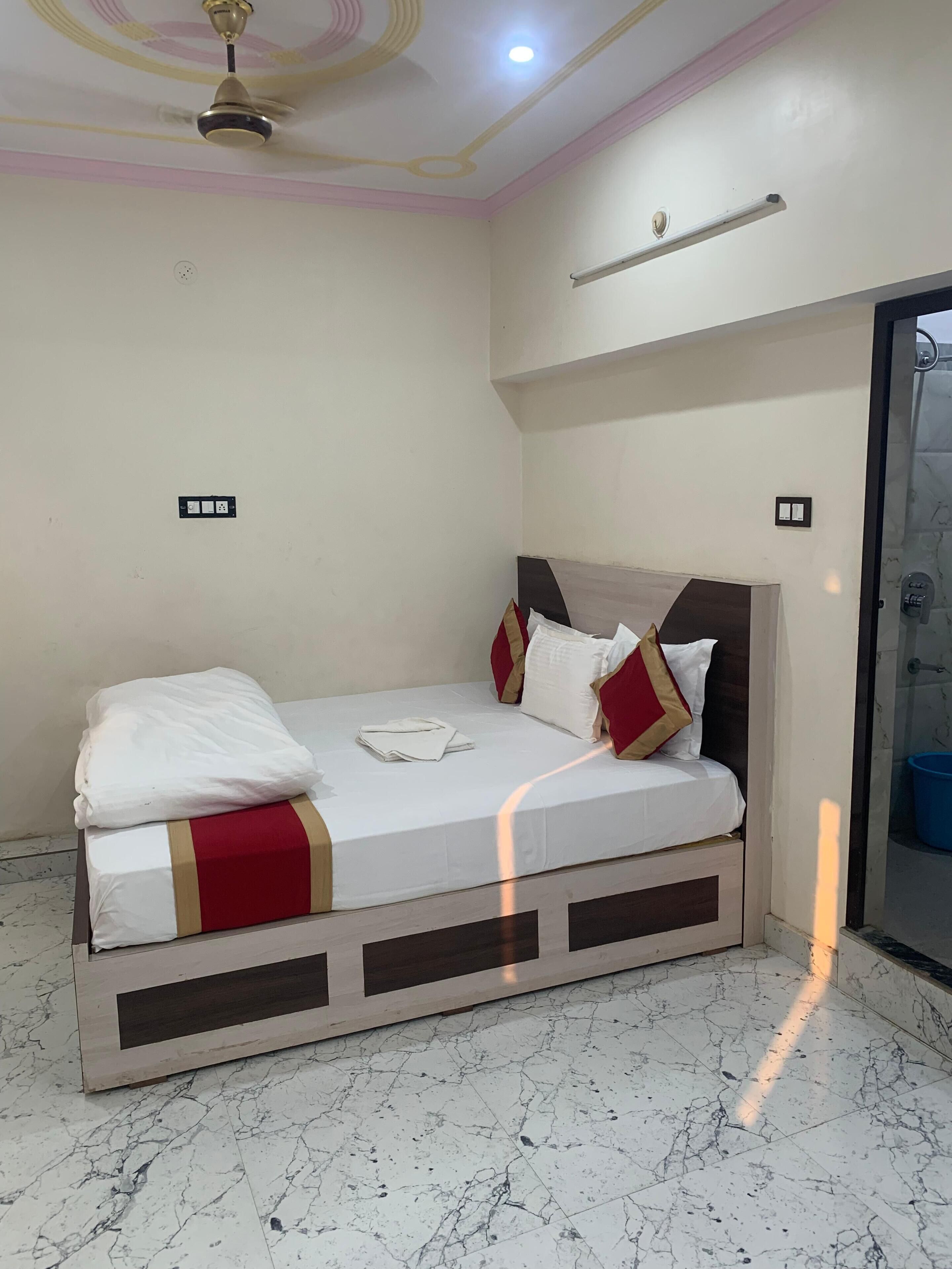 Una camera da letto con un letto, una ventola a soffitto, un lampadario e una porta che dà su un bagno.
