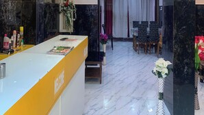 Un espace d’accueil doté d’un sol en marbre, d’un comptoir de réception et d’un coin repas avec une table et des chaises.