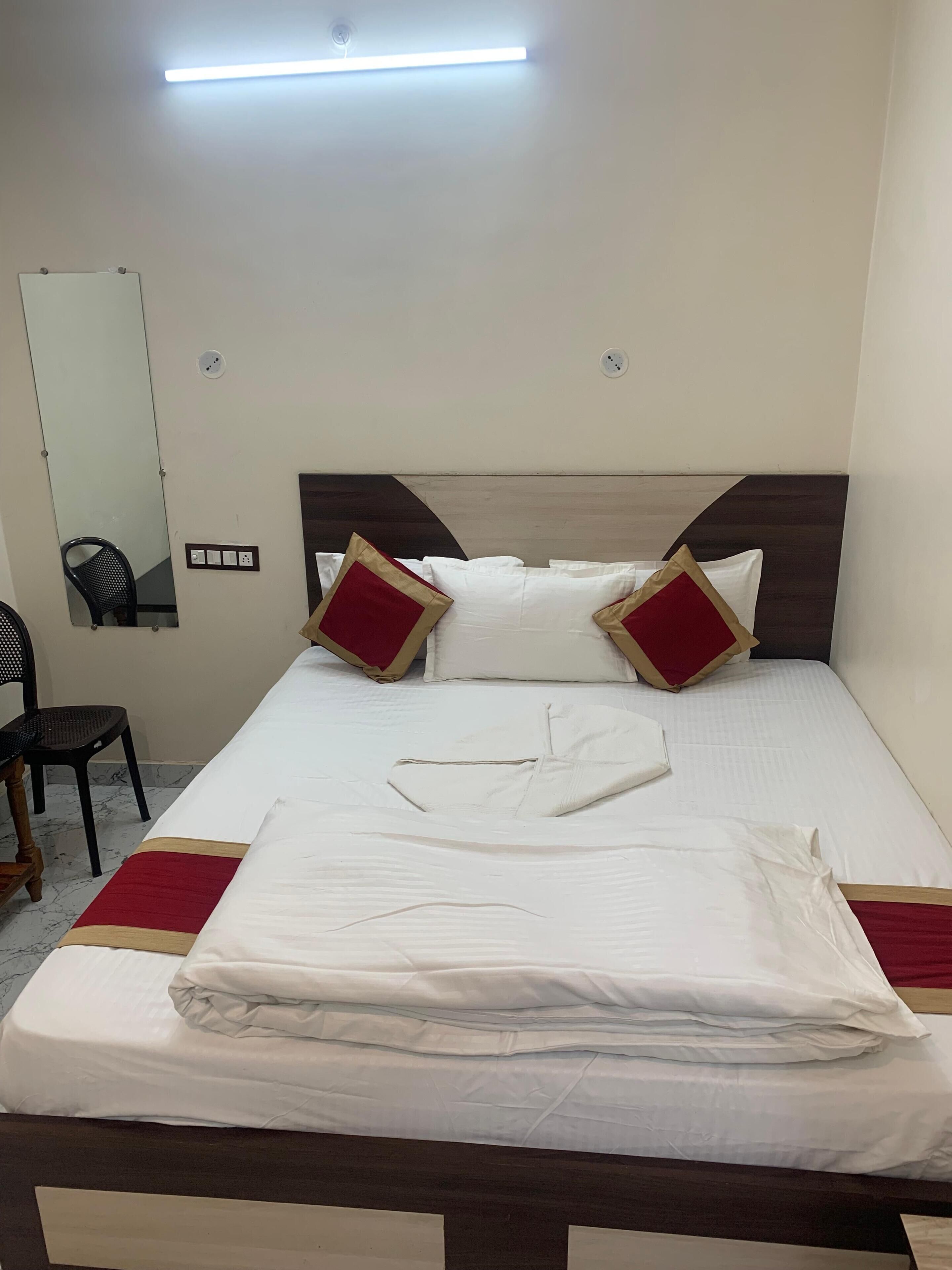 Una cama bien hecha con cabecera de madera, un espejo en la pared y una silla.