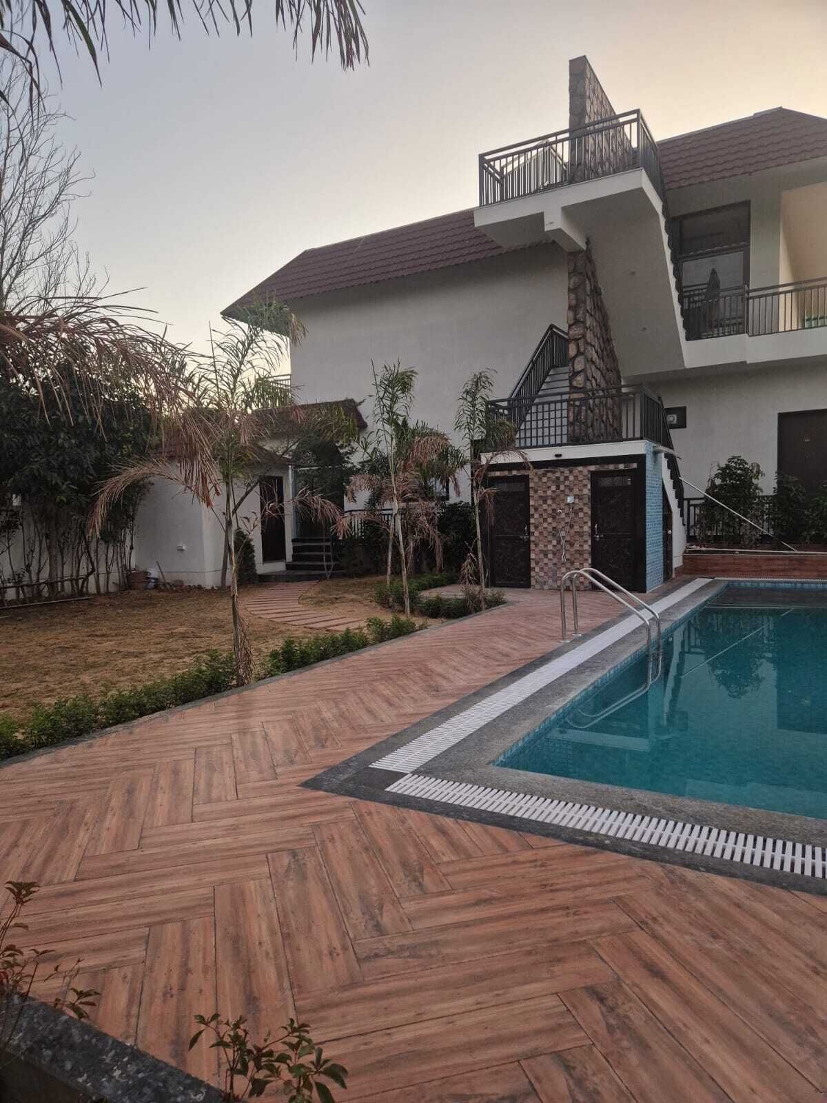 Una casa moderna con piscina, un patio cubierto y una chimenea de piedra.