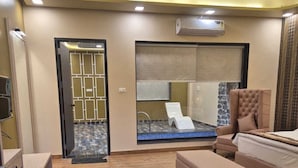 Une chambre d’hôtel moderne équipée d’un lit, d’un coin salon, d’une grande fenêtre et d’un ventilateur de plafond.