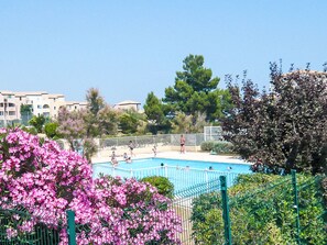 A swimming pool surrounded by a fence, with a clear blue sky above. - Les Terrasses de la M éditerranée by Interhome (Saint Pierre La Mer)