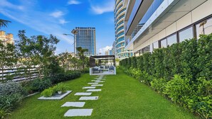 A modern outdoor area with a paved pathway, greenery, and a covered seating area. - Bloomfields Studio Condor Golf Links 18  (Dubai)