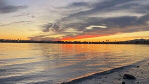 Un atardecer sobre un cuerpo de agua tranquilo con una costa distante.