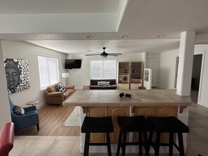 Eine moderne Küche mit Kochinsel, Barhocker, einer Couch und einem Fernseher.