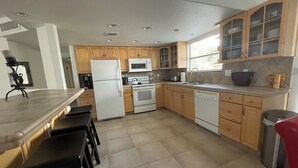 Una cocina con gabinetes de madera, refrigerador, microondas, estufa y lavavajillas.
