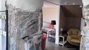 Una sala de estar moderna con una pared de acento de piedra, un sofá, una mesa de centro, una lámpara y un sillón.