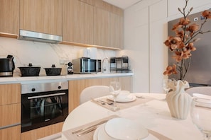 A modern kitchen with wooden cabinets, a stainless steel oven, a microwave, and a coffee maker. - FIRST CLASS | 1BR | Serenity Sea & Palm View (Dubai Harbour)