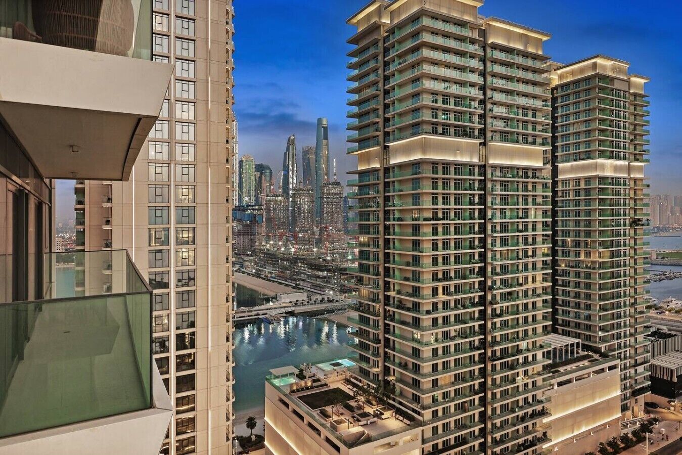 Un edificio de gran altura con múltiples balcones, vista a un cuerpo de agua y un paisaje urbano al fondo.