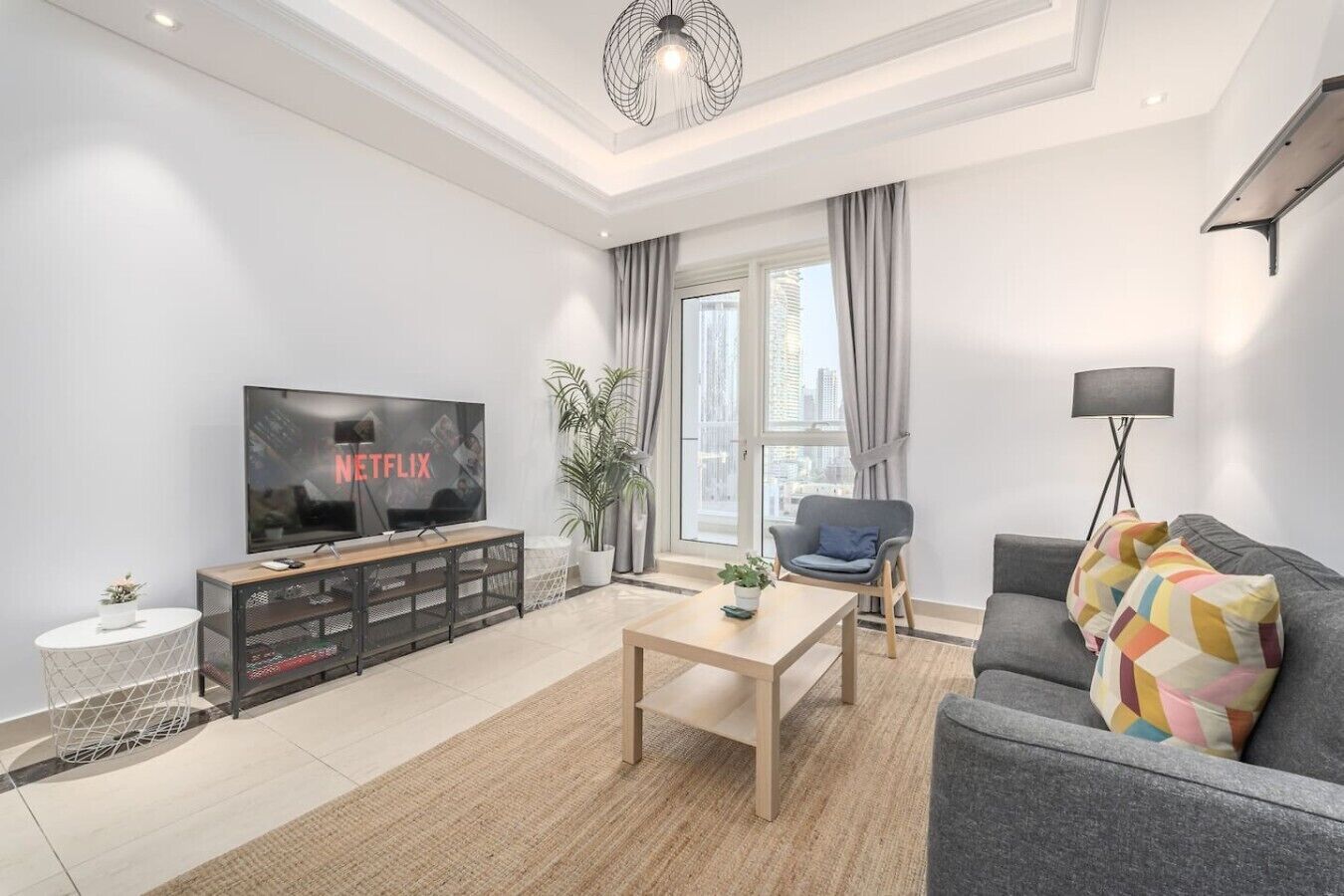 Un salon moderne avec un téléviseur à écran plat, un canapé, une table basse et une plante en pot.